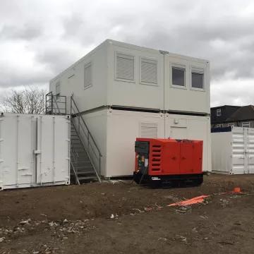 An Algeco Moduflex modular building site accommodation joined by a shipping container and generator